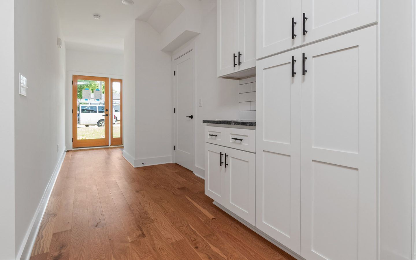 long kitchen with white cabinets and black hardware