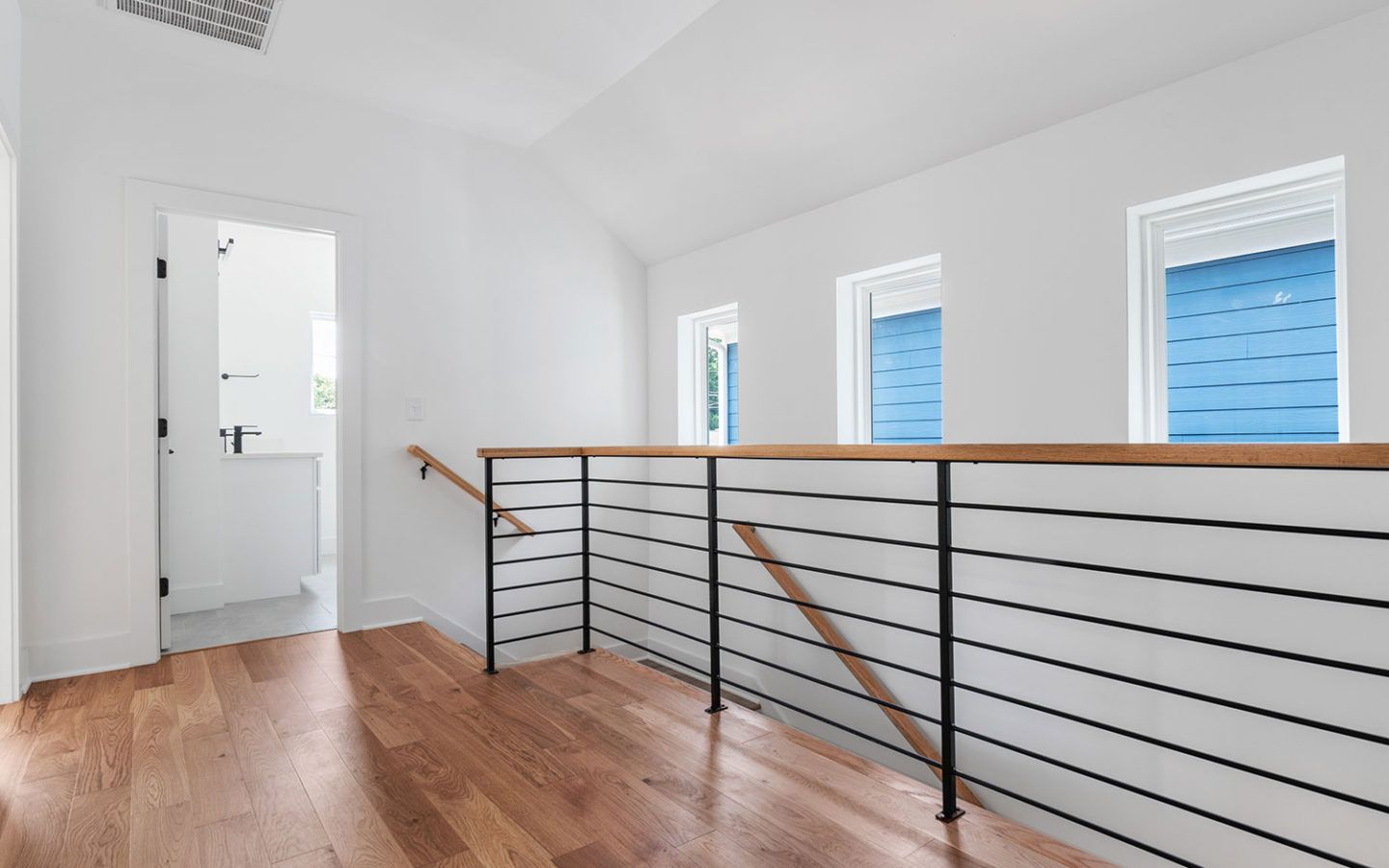 inside a freshly renovated home, showing stair railings and door open to bathroom